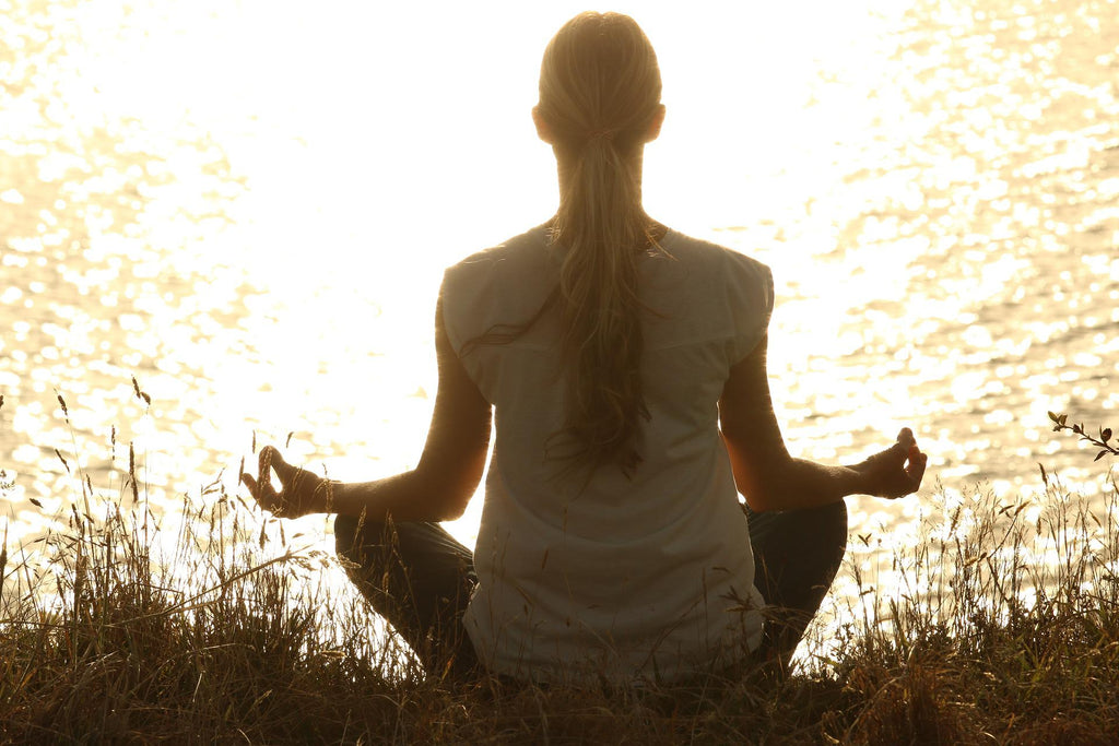 woman meditating by water